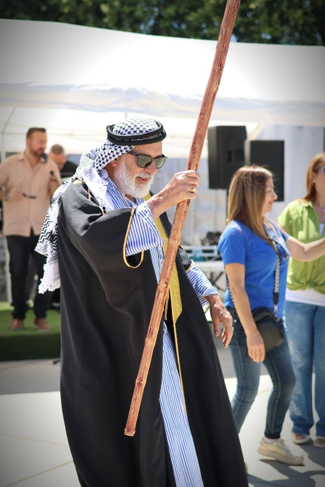 A dabke leader in a keffiyeh dancing with his staff