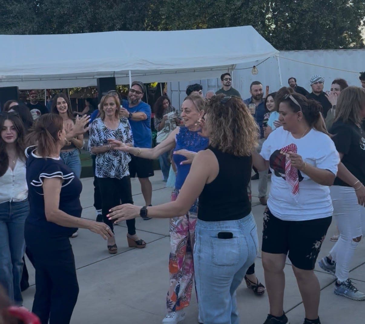 A circle of dancers in front of the tents